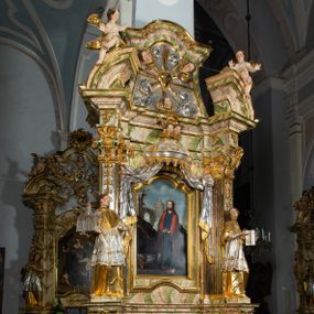 Zdjęcie nr 1: Ołtarz drewniany, prostopadłościenny z kamienną mensą, z kamiennym portatylem. Antepedium drewniane ujęte marmoryzowaną ramą z karbowanym profilem. W polu owalny medalion z przedstawieniem świętego z zakonu Marków, ujętym wicią akantową przeplatana z kwiatową. Nastawa ołtarzowa architektoniczna, jednoosiowa, jednokondygnacyjna ze zwieńczeniem na cokole.  Retabulum flankowane parą zdwojonych półfilarów zakończonych konsolami,  dźwigających pełne belkowanie oraz fragmenty przerwanego, półkolistego przyczółka z siedzącymi puttami. Na tle pilastrów, na konsolach ustawione figury dwóch świętych. Trzony pilastrów dekorowane kampanulami. W polu środkowym wnęka w formie stojącego prostokąta zamkniętego łukiem segmentowym nadwieszonego z uskokiem ujęta profilowaną ramą, z obrazem Wskrzeszenie Łazarza, w osobnej ramie. Nad wnęką baldachim dekorowany lambrekinem, z podwieszoną tkaniną po dwóch stronach, lamowaną frędzlą. Nam baldachimem kartusz z uskrzydlonymi główkami anielskimi i zwieńczony koroną. Zwieńczenie w formie zbliżonej do trapezu o wklęsłych bokach zamknięte falistym gzymsem, dekorowanym kampanulami. W polu gorejące serce przebite mieczem, w otoku z obłoków i uskrzydlonych główek anielskich, w glorii promienistej.  Struktura polichromowana w sposób imitujący marmoryzację w kolorze beżowo-zielonym. Ornamentyka i profile złocone, detal i zwieńczenie srebrzone.