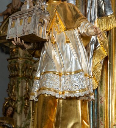 Zdjęcie nr 5: Ołtarz drewniany, prostopadłościenny z kamienną mensą, z kamiennym portatylem. Antepedium drewniane ujęte marmoryzowaną ramą z karbowanym profilem. W polu owalny medalion z przedstawieniem świętego z zakonu Marków, ujętym wicią akantową przeplatana z kwiatową. Nastawa ołtarzowa architektoniczna, jednoosiowa, jednokondygnacyjna ze zwieńczeniem na cokole.  Retabulum flankowane parą zdwojonych półfilarów zakończonych konsolami,  dźwigających pełne belkowanie oraz fragmenty przerwanego, półkolistego przyczółka z siedzącymi puttami. Na tle pilastrów, na konsolach ustawione figury dwóch świętych. Trzony pilastrów dekorowane kampanulami. W polu środkowym wnęka w formie stojącego prostokąta zamkniętego łukiem segmentowym nadwieszonego z uskokiem ujęta profilowaną ramą, z obrazem Wskrzeszenie Łazarza, w osobnej ramie. Nad wnęką baldachim dekorowany lambrekinem, z podwieszoną tkaniną po dwóch stronach, lamowaną frędzlą. Nam baldachimem kartusz z uskrzydlonymi główkami anielskimi i zwieńczony koroną. Zwieńczenie w formie zbliżonej do trapezu o wklęsłych bokach zamknięte falistym gzymsem, dekorowanym kampanulami. W polu gorejące serce przebite mieczem, w otoku z obłoków i uskrzydlonych główek anielskich, w glorii promienistej.  Struktura polichromowana w sposób imitujący marmoryzację w kolorze beżowo-zielonym. Ornamentyka i profile złocone, detal i zwieńczenie srebrzone.