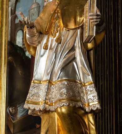 Zdjęcie nr 7: Ołtarz drewniany, prostopadłościenny z kamienną mensą, z kamiennym portatylem. Antepedium drewniane ujęte marmoryzowaną ramą z karbowanym profilem. W polu owalny medalion z przedstawieniem świętego z zakonu Marków, ujętym wicią akantową przeplatana z kwiatową. Nastawa ołtarzowa architektoniczna, jednoosiowa, jednokondygnacyjna ze zwieńczeniem na cokole.  Retabulum flankowane parą zdwojonych półfilarów zakończonych konsolami,  dźwigających pełne belkowanie oraz fragmenty przerwanego, półkolistego przyczółka z siedzącymi puttami. Na tle pilastrów, na konsolach ustawione figury dwóch świętych. Trzony pilastrów dekorowane kampanulami. W polu środkowym wnęka w formie stojącego prostokąta zamkniętego łukiem segmentowym nadwieszonego z uskokiem ujęta profilowaną ramą, z obrazem Wskrzeszenie Łazarza, w osobnej ramie. Nad wnęką baldachim dekorowany lambrekinem, z podwieszoną tkaniną po dwóch stronach, lamowaną frędzlą. Nam baldachimem kartusz z uskrzydlonymi główkami anielskimi i zwieńczony koroną. Zwieńczenie w formie zbliżonej do trapezu o wklęsłych bokach zamknięte falistym gzymsem, dekorowanym kampanulami. W polu gorejące serce przebite mieczem, w otoku z obłoków i uskrzydlonych główek anielskich, w glorii promienistej.  Struktura polichromowana w sposób imitujący marmoryzację w kolorze beżowo-zielonym. Ornamentyka i profile złocone, detal i zwieńczenie srebrzone.