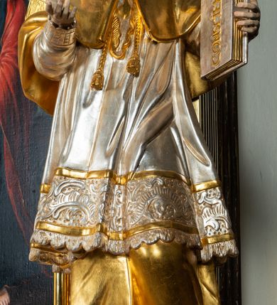 Zdjęcie nr 6: Ołtarz drewniany, prostopadłościenny z kamienną mensą, z kamiennym portatylem. Antepedium drewniane ujęte marmoryzowaną ramą z karbowanym profilem. W polu owalny medalion z przedstawieniem świętego z zakonu Marków, ujętym wicią akantową przeplatana z kwiatową. Nastawa ołtarzowa architektoniczna, jednoosiowa, jednokondygnacyjna ze zwieńczeniem na cokole.  Retabulum flankowane parą zdwojonych półfilarów zakończonych konsolami,  dźwigających pełne belkowanie oraz fragmenty przerwanego, półkolistego przyczółka z siedzącymi puttami. Na tle pilastrów, na konsolach ustawione figury dwóch świętych. Trzony pilastrów dekorowane kampanulami. W polu środkowym wnęka w formie stojącego prostokąta zamkniętego łukiem segmentowym nadwieszonego z uskokiem ujęta profilowaną ramą, z obrazem Wskrzeszenie Łazarza, w osobnej ramie. Nad wnęką baldachim dekorowany lambrekinem, z podwieszoną tkaniną po dwóch stronach, lamowaną frędzlą. Nam baldachimem kartusz z uskrzydlonymi główkami anielskimi i zwieńczony koroną. Zwieńczenie w formie zbliżonej do trapezu o wklęsłych bokach zamknięte falistym gzymsem, dekorowanym kampanulami. W polu gorejące serce przebite mieczem, w otoku z obłoków i uskrzydlonych główek anielskich, w glorii promienistej.  Struktura polichromowana w sposób imitujący marmoryzację w kolorze beżowo-zielonym. Ornamentyka i profile złocone, detal i zwieńczenie srebrzone.