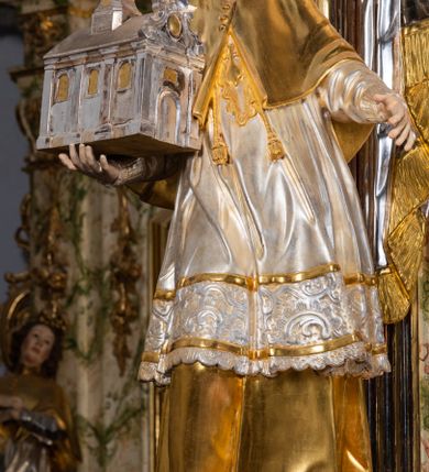 Zdjęcie nr 34: Ołtarz drewniany, prostopadłościenny z kamienną mensą, z kamiennym portatylem. Antepedium drewniane ujęte marmoryzowaną ramą z karbowanym profilem. W polu owalny medalion z przedstawieniem świętego z zakonu Marków, ujętym wicią akantową przeplatana z kwiatową. Nastawa ołtarzowa architektoniczna, jednoosiowa, jednokondygnacyjna ze zwieńczeniem na cokole.  Retabulum flankowane parą zdwojonych półfilarów zakończonych konsolami,  dźwigających pełne belkowanie oraz fragmenty przerwanego, półkolistego przyczółka z siedzącymi puttami. Na tle pilastrów, na konsolach ustawione figury dwóch świętych. Trzony pilastrów dekorowane kampanulami. W polu środkowym wnęka w formie stojącego prostokąta zamkniętego łukiem segmentowym nadwieszonego z uskokiem ujęta profilowaną ramą, z obrazem Wskrzeszenie Łazarza, w osobnej ramie. Nad wnęką baldachim dekorowany lambrekinem, z podwieszoną tkaniną po dwóch stronach, lamowaną frędzlą. Nam baldachimem kartusz z uskrzydlonymi główkami anielskimi i zwieńczony koroną. Zwieńczenie w formie zbliżonej do trapezu o wklęsłych bokach zamknięte falistym gzymsem, dekorowanym kampanulami. W polu gorejące serce przebite mieczem, w otoku z obłoków i uskrzydlonych główek anielskich, w glorii promienistej.  Struktura polichromowana w sposób imitujący marmoryzację w kolorze beżowo-zielonym. Ornamentyka i profile złocone, detal i zwieńczenie srebrzone.