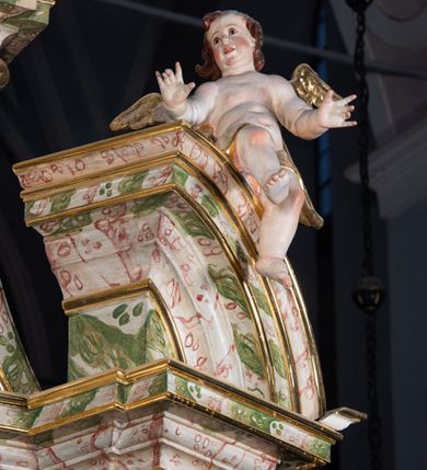 Zdjęcie nr 42: Ołtarz drewniany, prostopadłościenny z kamienną mensą, z kamiennym portatylem. Antepedium drewniane ujęte marmoryzowaną ramą z karbowanym profilem. W polu owalny medalion z przedstawieniem świętego z zakonu Marków, ujętym wicią akantową przeplatana z kwiatową. Nastawa ołtarzowa architektoniczna, jednoosiowa, jednokondygnacyjna ze zwieńczeniem na cokole.  Retabulum flankowane parą zdwojonych półfilarów zakończonych konsolami,  dźwigających pełne belkowanie oraz fragmenty przerwanego, półkolistego przyczółka z siedzącymi puttami. Na tle pilastrów, na konsolach ustawione figury dwóch świętych. Trzony pilastrów dekorowane kampanulami. W polu środkowym wnęka w formie stojącego prostokąta zamkniętego łukiem segmentowym nadwieszonego z uskokiem ujęta profilowaną ramą, z obrazem Wskrzeszenie Łazarza, w osobnej ramie. Nad wnęką baldachim dekorowany lambrekinem, z podwieszoną tkaniną po dwóch stronach, lamowaną frędzlą. Nam baldachimem kartusz z uskrzydlonymi główkami anielskimi i zwieńczony koroną. Zwieńczenie w formie zbliżonej do trapezu o wklęsłych bokach zamknięte falistym gzymsem, dekorowanym kampanulami. W polu gorejące serce przebite mieczem, w otoku z obłoków i uskrzydlonych główek anielskich, w glorii promienistej.  Struktura polichromowana w sposób imitujący marmoryzację w kolorze beżowo-zielonym. Ornamentyka i profile złocone, detal i zwieńczenie srebrzone.