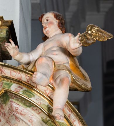 Zdjęcie nr 39: Ołtarz drewniany, prostopadłościenny z kamienną mensą, z kamiennym portatylem. Antepedium drewniane ujęte marmoryzowaną ramą z karbowanym profilem. W polu owalny medalion z przedstawieniem świętego z zakonu Marków, ujętym wicią akantową przeplatana z kwiatową. Nastawa ołtarzowa architektoniczna, jednoosiowa, jednokondygnacyjna ze zwieńczeniem na cokole.  Retabulum flankowane parą zdwojonych półfilarów zakończonych konsolami,  dźwigających pełne belkowanie oraz fragmenty przerwanego, półkolistego przyczółka z siedzącymi puttami. Na tle pilastrów, na konsolach ustawione figury dwóch świętych. Trzony pilastrów dekorowane kampanulami. W polu środkowym wnęka w formie stojącego prostokąta zamkniętego łukiem segmentowym nadwieszonego z uskokiem ujęta profilowaną ramą, z obrazem Wskrzeszenie Łazarza, w osobnej ramie. Nad wnęką baldachim dekorowany lambrekinem, z podwieszoną tkaniną po dwóch stronach, lamowaną frędzlą. Nam baldachimem kartusz z uskrzydlonymi główkami anielskimi i zwieńczony koroną. Zwieńczenie w formie zbliżonej do trapezu o wklęsłych bokach zamknięte falistym gzymsem, dekorowanym kampanulami. W polu gorejące serce przebite mieczem, w otoku z obłoków i uskrzydlonych główek anielskich, w glorii promienistej.  Struktura polichromowana w sposób imitujący marmoryzację w kolorze beżowo-zielonym. Ornamentyka i profile złocone, detal i zwieńczenie srebrzone.