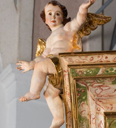 Zdjęcie nr 53: Ołtarz drewniany, prostopadłościenny z kamienną mensą, z kamiennym portatylem. Antepedium drewniane ujęte marmoryzowaną ramą z karbowanym profilem. W polu owalny medalion z przedstawieniem świętego z zakonu Marków, ujętym wicią akantową przeplatana z kwiatową. Nastawa ołtarzowa architektoniczna, jednoosiowa, jednokondygnacyjna ze zwieńczeniem na cokole.  Retabulum flankowane parą zdwojonych półfilarów zakończonych konsolami,  dźwigających pełne belkowanie oraz fragmenty przerwanego, półkolistego przyczółka z siedzącymi puttami. Na tle pilastrów, na konsolach ustawione figury dwóch świętych. Trzony pilastrów dekorowane kampanulami. W polu środkowym wnęka w formie stojącego prostokąta zamkniętego łukiem segmentowym nadwieszonego z uskokiem ujęta profilowaną ramą, z obrazem Wskrzeszenie Łazarza, w osobnej ramie. Nad wnęką baldachim dekorowany lambrekinem, z podwieszoną tkaniną po dwóch stronach, lamowaną frędzlą. Nam baldachimem kartusz z uskrzydlonymi główkami anielskimi i zwieńczony koroną. Zwieńczenie w formie zbliżonej do trapezu o wklęsłych bokach zamknięte falistym gzymsem, dekorowanym kampanulami. W polu gorejące serce przebite mieczem, w otoku z obłoków i uskrzydlonych główek anielskich, w glorii promienistej.  Struktura polichromowana w sposób imitujący marmoryzację w kolorze beżowo-zielonym. Ornamentyka i profile złocone, detal i zwieńczenie srebrzone.