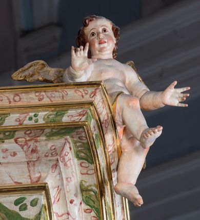 Zdjęcie nr 52: Ołtarz drewniany, prostopadłościenny z kamienną mensą, z kamiennym portatylem. Antepedium drewniane ujęte marmoryzowaną ramą z karbowanym profilem. W polu owalny medalion z przedstawieniem świętego z zakonu Marków, ujętym wicią akantową przeplatana z kwiatową. Nastawa ołtarzowa architektoniczna, jednoosiowa, jednokondygnacyjna ze zwieńczeniem na cokole.  Retabulum flankowane parą zdwojonych półfilarów zakończonych konsolami,  dźwigających pełne belkowanie oraz fragmenty przerwanego, półkolistego przyczółka z siedzącymi puttami. Na tle pilastrów, na konsolach ustawione figury dwóch świętych. Trzony pilastrów dekorowane kampanulami. W polu środkowym wnęka w formie stojącego prostokąta zamkniętego łukiem segmentowym nadwieszonego z uskokiem ujęta profilowaną ramą, z obrazem Wskrzeszenie Łazarza, w osobnej ramie. Nad wnęką baldachim dekorowany lambrekinem, z podwieszoną tkaniną po dwóch stronach, lamowaną frędzlą. Nam baldachimem kartusz z uskrzydlonymi główkami anielskimi i zwieńczony koroną. Zwieńczenie w formie zbliżonej do trapezu o wklęsłych bokach zamknięte falistym gzymsem, dekorowanym kampanulami. W polu gorejące serce przebite mieczem, w otoku z obłoków i uskrzydlonych główek anielskich, w glorii promienistej.  Struktura polichromowana w sposób imitujący marmoryzację w kolorze beżowo-zielonym. Ornamentyka i profile złocone, detal i zwieńczenie srebrzone.