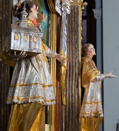 Zdjęcie nr 55: Ołtarz drewniany, prostopadłościenny z kamienną mensą, z kamiennym portatylem. Antepedium drewniane ujęte marmoryzowaną ramą z karbowanym profilem. W polu owalny medalion z przedstawieniem świętego z zakonu Marków, ujętym wicią akantową przeplatana z kwiatową. Nastawa ołtarzowa architektoniczna, jednoosiowa, jednokondygnacyjna ze zwieńczeniem na cokole.  Retabulum flankowane parą zdwojonych półfilarów zakończonych konsolami,  dźwigających pełne belkowanie oraz fragmenty przerwanego, półkolistego przyczółka z siedzącymi puttami. Na tle pilastrów, na konsolach ustawione figury dwóch świętych. Trzony pilastrów dekorowane kampanulami. W polu środkowym wnęka w formie stojącego prostokąta zamkniętego łukiem segmentowym nadwieszonego z uskokiem ujęta profilowaną ramą, z obrazem Wskrzeszenie Łazarza, w osobnej ramie. Nad wnęką baldachim dekorowany lambrekinem, z podwieszoną tkaniną po dwóch stronach, lamowaną frędzlą. Nam baldachimem kartusz z uskrzydlonymi główkami anielskimi i zwieńczony koroną. Zwieńczenie w formie zbliżonej do trapezu o wklęsłych bokach zamknięte falistym gzymsem, dekorowanym kampanulami. W polu gorejące serce przebite mieczem, w otoku z obłoków i uskrzydlonych główek anielskich, w glorii promienistej.  Struktura polichromowana w sposób imitujący marmoryzację w kolorze beżowo-zielonym. Ornamentyka i profile złocone, detal i zwieńczenie srebrzone.