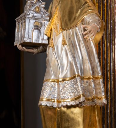 Zdjęcie nr 61: Ołtarz drewniany, prostopadłościenny z kamienną mensą, z kamiennym portatylem. Antepedium drewniane ujęte marmoryzowaną ramą z karbowanym profilem. W polu owalny medalion z przedstawieniem świętego z zakonu Marków, ujętym wicią akantową przeplatana z kwiatową. Nastawa ołtarzowa architektoniczna, jednoosiowa, jednokondygnacyjna ze zwieńczeniem na cokole.  Retabulum flankowane parą zdwojonych półfilarów zakończonych konsolami,  dźwigających pełne belkowanie oraz fragmenty przerwanego, półkolistego przyczółka z siedzącymi puttami. Na tle pilastrów, na konsolach ustawione figury dwóch świętych. Trzony pilastrów dekorowane kampanulami. W polu środkowym wnęka w formie stojącego prostokąta zamkniętego łukiem segmentowym nadwieszonego z uskokiem ujęta profilowaną ramą, z obrazem Wskrzeszenie Łazarza, w osobnej ramie. Nad wnęką baldachim dekorowany lambrekinem, z podwieszoną tkaniną po dwóch stronach, lamowaną frędzlą. Nam baldachimem kartusz z uskrzydlonymi główkami anielskimi i zwieńczony koroną. Zwieńczenie w formie zbliżonej do trapezu o wklęsłych bokach zamknięte falistym gzymsem, dekorowanym kampanulami. W polu gorejące serce przebite mieczem, w otoku z obłoków i uskrzydlonych główek anielskich, w glorii promienistej.  Struktura polichromowana w sposób imitujący marmoryzację w kolorze beżowo-zielonym. Ornamentyka i profile złocone, detal i zwieńczenie srebrzone.