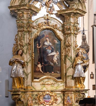 Zdjęcie nr 2: Ołtarz drewniany, prostopadłościenny z kamienną mensą, z kamiennym portatylem. Antepedium z prostokątną płyciną ujętą marmoryzowaną ramą ze złoconym karbowanym profilem. W polu przedstawienie świętej z aniołkiem podającym jej kosz kwiatów, flankowany akantową wicią akantową przeplataną z roślinną, na jasnoniebieskim tle, z datą „1754”. Nastawa ołtarzowa architektoniczna, jednoosiowa, jednokondygnacyjna ze zwieńczeniem na dwustrefowym cokole.  Retabulum flankowane parą opilastrowanych filarów, które dźwigają imposty oraz fragmenty przerwanego półkolistego przyczółka z siedzącymi puttami. Na tle filarów, na konsolach ustawione 2 figury św. Demetriusza i św. Selencjusza. Trzony pilastrów dekorowane zwisami kwiatowymi. W Polu środkowym wnęka w formie stojącego prostokąta zamkniętego łukiem segmentowym nadwieszonego z uskokiem ujęta profilowaną ramą, dekorowaną ornamentem roślinnym, z obrazem św. Heleny. Wnęka od dołu i góry flankowana ornamentem roślinnym i roccailem. Kondygnacja flankowana uszami utworzonymi z roccailu. Zwieńczenie w formie zbliżonej do trapezu o wklęsłych bokach zamknięte fragmentem gzymsu, wyłamanego na kształt łuku segmentowego nadwieszonego, z kartuszem z ornamentem roccailowym. W polu gorejące serce w otoku z obłoków i uskrzydlonych główek anielskich, w glorii promienistej.  Struktura polichromowana w sposób imitujący marmoryzację w kolorze beżowo-zielonym. Ornamentyka i profile złocone, detal i zwieńczenie srebrzone.