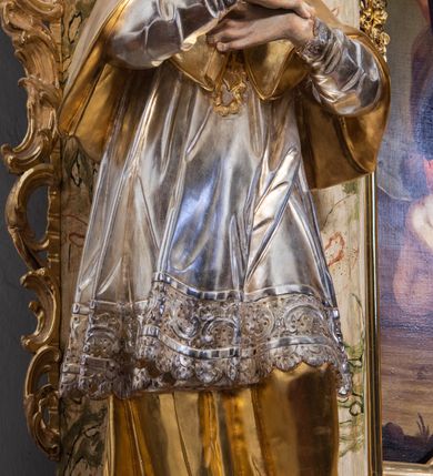 Zdjęcie nr 8: Ołtarz drewniany, prostopadłościenny z kamienną mensą, z kamiennym portatylem. Antepedium z prostokątną płyciną ujętą marmoryzowaną ramą ze złoconym karbowanym profilem. W polu przedstawienie świętej z aniołkiem podającym jej kosz kwiatów, flankowany akantową wicią akantową przeplataną z roślinną, na jasnoniebieskim tle, z datą „1754”. Nastawa ołtarzowa architektoniczna, jednoosiowa, jednokondygnacyjna ze zwieńczeniem na dwustrefowym cokole.  Retabulum flankowane parą opilastrowanych filarów, które dźwigają imposty oraz fragmenty przerwanego półkolistego przyczółka z siedzącymi puttami. Na tle filarów, na konsolach ustawione 2 figury św. Demetriusza i św. Selencjusza. Trzony pilastrów dekorowane zwisami kwiatowymi. W Polu środkowym wnęka w formie stojącego prostokąta zamkniętego łukiem segmentowym nadwieszonego z uskokiem ujęta profilowaną ramą, dekorowaną ornamentem roślinnym, z obrazem św. Heleny. Wnęka od dołu i góry flankowana ornamentem roślinnym i roccailem. Kondygnacja flankowana uszami utworzonymi z roccailu. Zwieńczenie w formie zbliżonej do trapezu o wklęsłych bokach zamknięte fragmentem gzymsu, wyłamanego na kształt łuku segmentowego nadwieszonego, z kartuszem z ornamentem roccailowym. W polu gorejące serce w otoku z obłoków i uskrzydlonych główek anielskich, w glorii promienistej.  Struktura polichromowana w sposób imitujący marmoryzację w kolorze beżowo-zielonym. Ornamentyka i profile złocone, detal i zwieńczenie srebrzone.