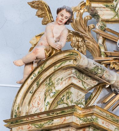 Zdjęcie nr 17: Ołtarz drewniany, prostopadłościenny z kamienną mensą, z kamiennym portatylem. Antepedium z prostokątną płyciną ujętą marmoryzowaną ramą ze złoconym karbowanym profilem. W polu przedstawienie świętej z aniołkiem podającym jej kosz kwiatów, flankowany akantową wicią akantową przeplataną z roślinną, na jasnoniebieskim tle, z datą „1754”. Nastawa ołtarzowa architektoniczna, jednoosiowa, jednokondygnacyjna ze zwieńczeniem na dwustrefowym cokole.  Retabulum flankowane parą opilastrowanych filarów, które dźwigają imposty oraz fragmenty przerwanego półkolistego przyczółka z siedzącymi puttami. Na tle filarów, na konsolach ustawione 2 figury św. Demetriusza i św. Selencjusza. Trzony pilastrów dekorowane zwisami kwiatowymi. W Polu środkowym wnęka w formie stojącego prostokąta zamkniętego łukiem segmentowym nadwieszonego z uskokiem ujęta profilowaną ramą, dekorowaną ornamentem roślinnym, z obrazem św. Heleny. Wnęka od dołu i góry flankowana ornamentem roślinnym i roccailem. Kondygnacja flankowana uszami utworzonymi z roccailu. Zwieńczenie w formie zbliżonej do trapezu o wklęsłych bokach zamknięte fragmentem gzymsu, wyłamanego na kształt łuku segmentowego nadwieszonego, z kartuszem z ornamentem roccailowym. W polu gorejące serce w otoku z obłoków i uskrzydlonych główek anielskich, w glorii promienistej.  Struktura polichromowana w sposób imitujący marmoryzację w kolorze beżowo-zielonym. Ornamentyka i profile złocone, detal i zwieńczenie srebrzone.