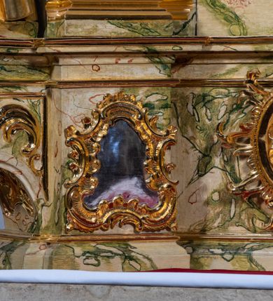 Zdjęcie nr 20: Ołtarz drewniany, prostopadłościenny z kamienną mensą, z kamiennym portatylem. Antepedium z prostokątną płyciną ujętą marmoryzowaną ramą ze złoconym karbowanym profilem. W polu przedstawienie świętej z aniołkiem podającym jej kosz kwiatów, flankowany akantową wicią akantową przeplataną z roślinną, na jasnoniebieskim tle, z datą „1754”. Nastawa ołtarzowa architektoniczna, jednoosiowa, jednokondygnacyjna ze zwieńczeniem na dwustrefowym cokole.  Retabulum flankowane parą opilastrowanych filarów, które dźwigają imposty oraz fragmenty przerwanego półkolistego przyczółka z siedzącymi puttami. Na tle filarów, na konsolach ustawione 2 figury św. Demetriusza i św. Selencjusza. Trzony pilastrów dekorowane zwisami kwiatowymi. W Polu środkowym wnęka w formie stojącego prostokąta zamkniętego łukiem segmentowym nadwieszonego z uskokiem ujęta profilowaną ramą, dekorowaną ornamentem roślinnym, z obrazem św. Heleny. Wnęka od dołu i góry flankowana ornamentem roślinnym i roccailem. Kondygnacja flankowana uszami utworzonymi z roccailu. Zwieńczenie w formie zbliżonej do trapezu o wklęsłych bokach zamknięte fragmentem gzymsu, wyłamanego na kształt łuku segmentowego nadwieszonego, z kartuszem z ornamentem roccailowym. W polu gorejące serce w otoku z obłoków i uskrzydlonych główek anielskich, w glorii promienistej.  Struktura polichromowana w sposób imitujący marmoryzację w kolorze beżowo-zielonym. Ornamentyka i profile złocone, detal i zwieńczenie srebrzone.