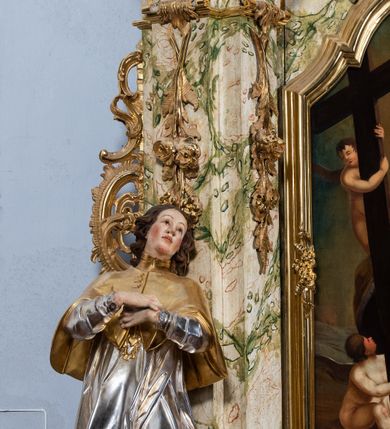 Zdjęcie nr 16: Ołtarz drewniany, prostopadłościenny z kamienną mensą, z kamiennym portatylem. Antepedium z prostokątną płyciną ujętą marmoryzowaną ramą ze złoconym karbowanym profilem. W polu przedstawienie świętej z aniołkiem podającym jej kosz kwiatów, flankowany akantową wicią akantową przeplataną z roślinną, na jasnoniebieskim tle, z datą „1754”. Nastawa ołtarzowa architektoniczna, jednoosiowa, jednokondygnacyjna ze zwieńczeniem na dwustrefowym cokole.  Retabulum flankowane parą opilastrowanych filarów, które dźwigają imposty oraz fragmenty przerwanego półkolistego przyczółka z siedzącymi puttami. Na tle filarów, na konsolach ustawione 2 figury św. Demetriusza i św. Selencjusza. Trzony pilastrów dekorowane zwisami kwiatowymi. W Polu środkowym wnęka w formie stojącego prostokąta zamkniętego łukiem segmentowym nadwieszonego z uskokiem ujęta profilowaną ramą, dekorowaną ornamentem roślinnym, z obrazem św. Heleny. Wnęka od dołu i góry flankowana ornamentem roślinnym i roccailem. Kondygnacja flankowana uszami utworzonymi z roccailu. Zwieńczenie w formie zbliżonej do trapezu o wklęsłych bokach zamknięte fragmentem gzymsu, wyłamanego na kształt łuku segmentowego nadwieszonego, z kartuszem z ornamentem roccailowym. W polu gorejące serce w otoku z obłoków i uskrzydlonych główek anielskich, w glorii promienistej.  Struktura polichromowana w sposób imitujący marmoryzację w kolorze beżowo-zielonym. Ornamentyka i profile złocone, detal i zwieńczenie srebrzone.