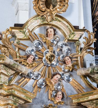 Zdjęcie nr 18: Ołtarz drewniany, prostopadłościenny z kamienną mensą, z kamiennym portatylem. Antepedium z prostokątną płyciną ujętą marmoryzowaną ramą ze złoconym karbowanym profilem. W polu przedstawienie świętej z aniołkiem podającym jej kosz kwiatów, flankowany akantową wicią akantową przeplataną z roślinną, na jasnoniebieskim tle, z datą „1754”. Nastawa ołtarzowa architektoniczna, jednoosiowa, jednokondygnacyjna ze zwieńczeniem na dwustrefowym cokole.  Retabulum flankowane parą opilastrowanych filarów, które dźwigają imposty oraz fragmenty przerwanego półkolistego przyczółka z siedzącymi puttami. Na tle filarów, na konsolach ustawione 2 figury św. Demetriusza i św. Selencjusza. Trzony pilastrów dekorowane zwisami kwiatowymi. W Polu środkowym wnęka w formie stojącego prostokąta zamkniętego łukiem segmentowym nadwieszonego z uskokiem ujęta profilowaną ramą, dekorowaną ornamentem roślinnym, z obrazem św. Heleny. Wnęka od dołu i góry flankowana ornamentem roślinnym i roccailem. Kondygnacja flankowana uszami utworzonymi z roccailu. Zwieńczenie w formie zbliżonej do trapezu o wklęsłych bokach zamknięte fragmentem gzymsu, wyłamanego na kształt łuku segmentowego nadwieszonego, z kartuszem z ornamentem roccailowym. W polu gorejące serce w otoku z obłoków i uskrzydlonych główek anielskich, w glorii promienistej.  Struktura polichromowana w sposób imitujący marmoryzację w kolorze beżowo-zielonym. Ornamentyka i profile złocone, detal i zwieńczenie srebrzone.