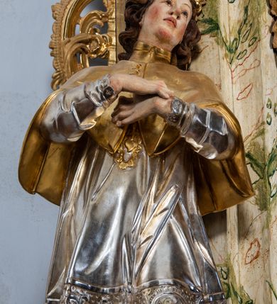 Zdjęcie nr 30: Ołtarz drewniany, prostopadłościenny z kamienną mensą, z kamiennym portatylem. Antepedium z prostokątną płyciną ujętą marmoryzowaną ramą ze złoconym karbowanym profilem. W polu przedstawienie świętej z aniołkiem podającym jej kosz kwiatów, flankowany akantową wicią akantową przeplataną z roślinną, na jasnoniebieskim tle, z datą „1754”. Nastawa ołtarzowa architektoniczna, jednoosiowa, jednokondygnacyjna ze zwieńczeniem na dwustrefowym cokole.  Retabulum flankowane parą opilastrowanych filarów, które dźwigają imposty oraz fragmenty przerwanego półkolistego przyczółka z siedzącymi puttami. Na tle filarów, na konsolach ustawione 2 figury św. Demetriusza i św. Selencjusza. Trzony pilastrów dekorowane zwisami kwiatowymi. W Polu środkowym wnęka w formie stojącego prostokąta zamkniętego łukiem segmentowym nadwieszonego z uskokiem ujęta profilowaną ramą, dekorowaną ornamentem roślinnym, z obrazem św. Heleny. Wnęka od dołu i góry flankowana ornamentem roślinnym i roccailem. Kondygnacja flankowana uszami utworzonymi z roccailu. Zwieńczenie w formie zbliżonej do trapezu o wklęsłych bokach zamknięte fragmentem gzymsu, wyłamanego na kształt łuku segmentowego nadwieszonego, z kartuszem z ornamentem roccailowym. W polu gorejące serce w otoku z obłoków i uskrzydlonych główek anielskich, w glorii promienistej.  Struktura polichromowana w sposób imitujący marmoryzację w kolorze beżowo-zielonym. Ornamentyka i profile złocone, detal i zwieńczenie srebrzone.