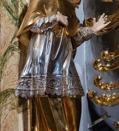 Zdjęcie nr 34: Ołtarz drewniany, prostopadłościenny z kamienną mensą, z kamiennym portatylem. Antepedium z prostokątną płyciną ujętą marmoryzowaną ramą ze złoconym karbowanym profilem. W polu przedstawienie świętej z aniołkiem podającym jej kosz kwiatów, flankowany akantową wicią akantową przeplataną z roślinną, na jasnoniebieskim tle, z datą „1754”. Nastawa ołtarzowa architektoniczna, jednoosiowa, jednokondygnacyjna ze zwieńczeniem na dwustrefowym cokole.  Retabulum flankowane parą opilastrowanych filarów, które dźwigają imposty oraz fragmenty przerwanego półkolistego przyczółka z siedzącymi puttami. Na tle filarów, na konsolach ustawione 2 figury św. Demetriusza i św. Selencjusza. Trzony pilastrów dekorowane zwisami kwiatowymi. W Polu środkowym wnęka w formie stojącego prostokąta zamkniętego łukiem segmentowym nadwieszonego z uskokiem ujęta profilowaną ramą, dekorowaną ornamentem roślinnym, z obrazem św. Heleny. Wnęka od dołu i góry flankowana ornamentem roślinnym i roccailem. Kondygnacja flankowana uszami utworzonymi z roccailu. Zwieńczenie w formie zbliżonej do trapezu o wklęsłych bokach zamknięte fragmentem gzymsu, wyłamanego na kształt łuku segmentowego nadwieszonego, z kartuszem z ornamentem roccailowym. W polu gorejące serce w otoku z obłoków i uskrzydlonych główek anielskich, w glorii promienistej.  Struktura polichromowana w sposób imitujący marmoryzację w kolorze beżowo-zielonym. Ornamentyka i profile złocone, detal i zwieńczenie srebrzone.