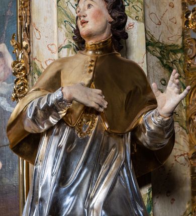 Zdjęcie nr 31: Ołtarz drewniany, prostopadłościenny z kamienną mensą, z kamiennym portatylem. Antepedium z prostokątną płyciną ujętą marmoryzowaną ramą ze złoconym karbowanym profilem. W polu przedstawienie świętej z aniołkiem podającym jej kosz kwiatów, flankowany akantową wicią akantową przeplataną z roślinną, na jasnoniebieskim tle, z datą „1754”. Nastawa ołtarzowa architektoniczna, jednoosiowa, jednokondygnacyjna ze zwieńczeniem na dwustrefowym cokole.  Retabulum flankowane parą opilastrowanych filarów, które dźwigają imposty oraz fragmenty przerwanego półkolistego przyczółka z siedzącymi puttami. Na tle filarów, na konsolach ustawione 2 figury św. Demetriusza i św. Selencjusza. Trzony pilastrów dekorowane zwisami kwiatowymi. W Polu środkowym wnęka w formie stojącego prostokąta zamkniętego łukiem segmentowym nadwieszonego z uskokiem ujęta profilowaną ramą, dekorowaną ornamentem roślinnym, z obrazem św. Heleny. Wnęka od dołu i góry flankowana ornamentem roślinnym i roccailem. Kondygnacja flankowana uszami utworzonymi z roccailu. Zwieńczenie w formie zbliżonej do trapezu o wklęsłych bokach zamknięte fragmentem gzymsu, wyłamanego na kształt łuku segmentowego nadwieszonego, z kartuszem z ornamentem roccailowym. W polu gorejące serce w otoku z obłoków i uskrzydlonych główek anielskich, w glorii promienistej.  Struktura polichromowana w sposób imitujący marmoryzację w kolorze beżowo-zielonym. Ornamentyka i profile złocone, detal i zwieńczenie srebrzone.