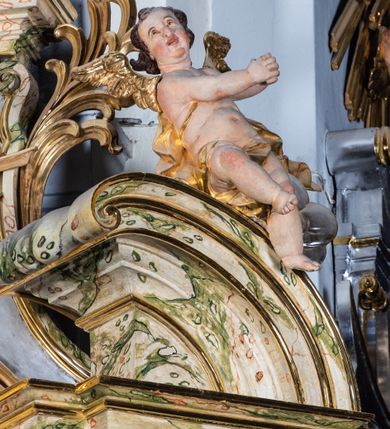Zdjęcie nr 38: Ołtarz drewniany, prostopadłościenny z kamienną mensą, z kamiennym portatylem. Antepedium z prostokątną płyciną ujętą marmoryzowaną ramą ze złoconym karbowanym profilem. W polu przedstawienie świętej z aniołkiem podającym jej kosz kwiatów, flankowany akantową wicią akantową przeplataną z roślinną, na jasnoniebieskim tle, z datą „1754”. Nastawa ołtarzowa architektoniczna, jednoosiowa, jednokondygnacyjna ze zwieńczeniem na dwustrefowym cokole.  Retabulum flankowane parą opilastrowanych filarów, które dźwigają imposty oraz fragmenty przerwanego półkolistego przyczółka z siedzącymi puttami. Na tle filarów, na konsolach ustawione 2 figury św. Demetriusza i św. Selencjusza. Trzony pilastrów dekorowane zwisami kwiatowymi. W Polu środkowym wnęka w formie stojącego prostokąta zamkniętego łukiem segmentowym nadwieszonego z uskokiem ujęta profilowaną ramą, dekorowaną ornamentem roślinnym, z obrazem św. Heleny. Wnęka od dołu i góry flankowana ornamentem roślinnym i roccailem. Kondygnacja flankowana uszami utworzonymi z roccailu. Zwieńczenie w formie zbliżonej do trapezu o wklęsłych bokach zamknięte fragmentem gzymsu, wyłamanego na kształt łuku segmentowego nadwieszonego, z kartuszem z ornamentem roccailowym. W polu gorejące serce w otoku z obłoków i uskrzydlonych główek anielskich, w glorii promienistej.  Struktura polichromowana w sposób imitujący marmoryzację w kolorze beżowo-zielonym. Ornamentyka i profile złocone, detal i zwieńczenie srebrzone.