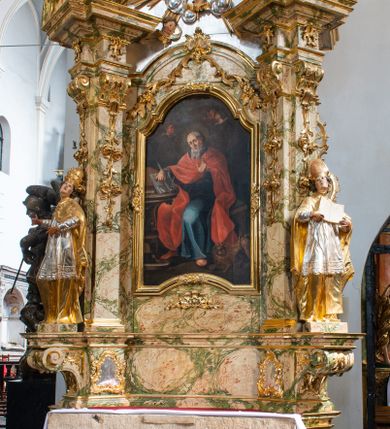 Zdjęcie nr 1: Ołtarz drewniany, prostopadłościenny z kamienną mensą, z kamiennym portatylem. Antependium z prostokątną płyciną ujętą marmoryzowaną ramą ze złoconym karbowanym profilem. W polu medalion w formie stojącego owalu z przedstawieniem zakonnika z dzieciątkiem, flankowany akantową wicią akantową przeplataną z roślinną, na jasnoniebieskim tle. Nastawa ołtarzowa architektoniczna, jednoosiowa, jednokondygnacyjna ze zwieńczeniem na dwustrefowym cokole.  Retabulum flankowane parą opilastrowanych filarów, które dźwigają imposty oraz fragmenty przerwanego półkolistego przyczółka z siedzącymi puttami. Na tle filarów, na konsolach ustawione 2 figury papieża i biskupa. Trzony pilastrów dekorowane zwisami kwiatowymi. W Polu środkowym wnęka w formie stojącego prostokąta zamkniętego łukiem segmentowym nadwieszonego z uskokiem ujęta profilowaną ramą, dekorowaną ornamentem roślinnym, z obrazem świętego Marka. Wnęka od dołu i góry flankowana ornamentem roślinnym i roccailem. Kondygnacja flankowana uszami utworzonymi z roccailu. Zwieńczenie w formie zbliżonej do trapezu o wklęsłych bokach zamknięte fragmentem gzymsu, wyłamanego na kształt łuku segmentowego nadwieszonego, z kartuszem z ornamentem roccailowym. W polu gorejące serce w otoku z obłoków i uskrzydlonych główek anielskich, w glorii promienistej.  Struktura polichromowana w sposób imitujący marmoryzację w kolorze beżowo-zielonym. Ornamentyka i profile złocone, detal i zwieńczenie srebrzone.