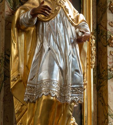 Zdjęcie nr 26: Ołtarz drewniany, prostopadłościenny z kamienną mensą, z kamiennym portatylem. Antependium z prostokątną płyciną ujętą marmoryzowaną ramą ze złoconym karbowanym profilem. W polu medalion w formie stojącego owalu z przedstawieniem zakonnika z dzieciątkiem, flankowany akantową wicią akantową przeplataną z roślinną, na jasnoniebieskim tle. Nastawa ołtarzowa architektoniczna, jednoosiowa, jednokondygnacyjna ze zwieńczeniem na dwustrefowym cokole.  Retabulum flankowane parą opilastrowanych filarów, które dźwigają imposty oraz fragmenty przerwanego półkolistego przyczółka z siedzącymi puttami. Na tle filarów, na konsolach ustawione 2 figury papieża i biskupa. Trzony pilastrów dekorowane zwisami kwiatowymi. W Polu środkowym wnęka w formie stojącego prostokąta zamkniętego łukiem segmentowym nadwieszonego z uskokiem ujęta profilowaną ramą, dekorowaną ornamentem roślinnym, z obrazem świętego Marka. Wnęka od dołu i góry flankowana ornamentem roślinnym i roccailem. Kondygnacja flankowana uszami utworzonymi z roccailu. Zwieńczenie w formie zbliżonej do trapezu o wklęsłych bokach zamknięte fragmentem gzymsu, wyłamanego na kształt łuku segmentowego nadwieszonego, z kartuszem z ornamentem roccailowym. W polu gorejące serce w otoku z obłoków i uskrzydlonych główek anielskich, w glorii promienistej.  Struktura polichromowana w sposób imitujący marmoryzację w kolorze beżowo-zielonym. Ornamentyka i profile złocone, detal i zwieńczenie srebrzone.