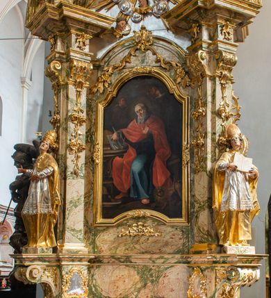 Zdjęcie nr 2: Ołtarz drewniany, prostopadłościenny z kamienną mensą, z kamiennym portatylem. Antependium z prostokątną płyciną ujętą marmoryzowaną ramą ze złoconym karbowanym profilem. W polu medalion w formie stojącego owalu z przedstawieniem zakonnika z dzieciątkiem, flankowany akantową wicią akantową przeplataną z roślinną, na jasnoniebieskim tle. Nastawa ołtarzowa architektoniczna, jednoosiowa, jednokondygnacyjna ze zwieńczeniem na dwustrefowym cokole.  Retabulum flankowane parą opilastrowanych filarów, które dźwigają imposty oraz fragmenty przerwanego półkolistego przyczółka z siedzącymi puttami. Na tle filarów, na konsolach ustawione 2 figury papieża i biskupa. Trzony pilastrów dekorowane zwisami kwiatowymi. W Polu środkowym wnęka w formie stojącego prostokąta zamkniętego łukiem segmentowym nadwieszonego z uskokiem ujęta profilowaną ramą, dekorowaną ornamentem roślinnym, z obrazem świętego Marka. Wnęka od dołu i góry flankowana ornamentem roślinnym i roccailem. Kondygnacja flankowana uszami utworzonymi z roccailu. Zwieńczenie w formie zbliżonej do trapezu o wklęsłych bokach zamknięte fragmentem gzymsu, wyłamanego na kształt łuku segmentowego nadwieszonego, z kartuszem z ornamentem roccailowym. W polu gorejące serce w otoku z obłoków i uskrzydlonych główek anielskich, w glorii promienistej.  Struktura polichromowana w sposób imitujący marmoryzację w kolorze beżowo-zielonym. Ornamentyka i profile złocone, detal i zwieńczenie srebrzone.