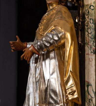 Zdjęcie nr 30: Ołtarz drewniany, prostopadłościenny z kamienną mensą, z kamiennym portatylem. Antependium z prostokątną płyciną ujętą marmoryzowaną ramą ze złoconym karbowanym profilem. W polu medalion w formie stojącego owalu z przedstawieniem zakonnika z dzieciątkiem, flankowany akantową wicią akantową przeplataną z roślinną, na jasnoniebieskim tle. Nastawa ołtarzowa architektoniczna, jednoosiowa, jednokondygnacyjna ze zwieńczeniem na dwustrefowym cokole.  Retabulum flankowane parą opilastrowanych filarów, które dźwigają imposty oraz fragmenty przerwanego półkolistego przyczółka z siedzącymi puttami. Na tle filarów, na konsolach ustawione 2 figury papieża i biskupa. Trzony pilastrów dekorowane zwisami kwiatowymi. W Polu środkowym wnęka w formie stojącego prostokąta zamkniętego łukiem segmentowym nadwieszonego z uskokiem ujęta profilowaną ramą, dekorowaną ornamentem roślinnym, z obrazem świętego Marka. Wnęka od dołu i góry flankowana ornamentem roślinnym i roccailem. Kondygnacja flankowana uszami utworzonymi z roccailu. Zwieńczenie w formie zbliżonej do trapezu o wklęsłych bokach zamknięte fragmentem gzymsu, wyłamanego na kształt łuku segmentowego nadwieszonego, z kartuszem z ornamentem roccailowym. W polu gorejące serce w otoku z obłoków i uskrzydlonych główek anielskich, w glorii promienistej.  Struktura polichromowana w sposób imitujący marmoryzację w kolorze beżowo-zielonym. Ornamentyka i profile złocone, detal i zwieńczenie srebrzone.