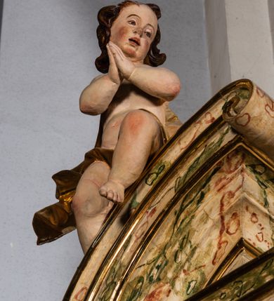 Zdjęcie nr 9: Ołtarz drewniany, prostopadłościenny z kamienną mensą, z kamiennym portatylem. Antependium z prostokątną płyciną ujętą marmoryzowaną ramą ze złoconym karbowanym profilem. W polu medalion w formie stojącego owalu z przedstawieniem zakonnika z dzieciątkiem, flankowany akantową wicią akantową przeplataną z roślinną, na jasnoniebieskim tle. Nastawa ołtarzowa architektoniczna, jednoosiowa, jednokondygnacyjna ze zwieńczeniem na dwustrefowym cokole.  Retabulum flankowane parą opilastrowanych filarów, które dźwigają imposty oraz fragmenty przerwanego półkolistego przyczółka z siedzącymi puttami. Na tle filarów, na konsolach ustawione 2 figury papieża i biskupa. Trzony pilastrów dekorowane zwisami kwiatowymi. W Polu środkowym wnęka w formie stojącego prostokąta zamkniętego łukiem segmentowym nadwieszonego z uskokiem ujęta profilowaną ramą, dekorowaną ornamentem roślinnym, z obrazem świętego Marka. Wnęka od dołu i góry flankowana ornamentem roślinnym i roccailem. Kondygnacja flankowana uszami utworzonymi z roccailu. Zwieńczenie w formie zbliżonej do trapezu o wklęsłych bokach zamknięte fragmentem gzymsu, wyłamanego na kształt łuku segmentowego nadwieszonego, z kartuszem z ornamentem roccailowym. W polu gorejące serce w otoku z obłoków i uskrzydlonych główek anielskich, w glorii promienistej.  Struktura polichromowana w sposób imitujący marmoryzację w kolorze beżowo-zielonym. Ornamentyka i profile złocone, detal i zwieńczenie srebrzone.