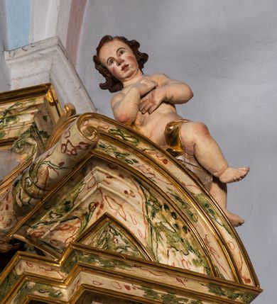 Zdjęcie nr 11: Ołtarz drewniany, prostopadłościenny z kamienną mensą, z kamiennym portatylem. Antependium z prostokątną płyciną ujętą marmoryzowaną ramą ze złoconym karbowanym profilem. W polu medalion w formie stojącego owalu z przedstawieniem zakonnika z dzieciątkiem, flankowany akantową wicią akantową przeplataną z roślinną, na jasnoniebieskim tle. Nastawa ołtarzowa architektoniczna, jednoosiowa, jednokondygnacyjna ze zwieńczeniem na dwustrefowym cokole.  Retabulum flankowane parą opilastrowanych filarów, które dźwigają imposty oraz fragmenty przerwanego półkolistego przyczółka z siedzącymi puttami. Na tle filarów, na konsolach ustawione 2 figury papieża i biskupa. Trzony pilastrów dekorowane zwisami kwiatowymi. W Polu środkowym wnęka w formie stojącego prostokąta zamkniętego łukiem segmentowym nadwieszonego z uskokiem ujęta profilowaną ramą, dekorowaną ornamentem roślinnym, z obrazem świętego Marka. Wnęka od dołu i góry flankowana ornamentem roślinnym i roccailem. Kondygnacja flankowana uszami utworzonymi z roccailu. Zwieńczenie w formie zbliżonej do trapezu o wklęsłych bokach zamknięte fragmentem gzymsu, wyłamanego na kształt łuku segmentowego nadwieszonego, z kartuszem z ornamentem roccailowym. W polu gorejące serce w otoku z obłoków i uskrzydlonych główek anielskich, w glorii promienistej.  Struktura polichromowana w sposób imitujący marmoryzację w kolorze beżowo-zielonym. Ornamentyka i profile złocone, detal i zwieńczenie srebrzone.