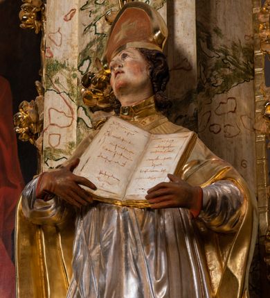 Zdjęcie nr 22: Ołtarz drewniany, prostopadłościenny z kamienną mensą, z kamiennym portatylem. Antependium z prostokątną płyciną ujętą marmoryzowaną ramą ze złoconym karbowanym profilem. W polu medalion w formie stojącego owalu z przedstawieniem zakonnika z dzieciątkiem, flankowany akantową wicią akantową przeplataną z roślinną, na jasnoniebieskim tle. Nastawa ołtarzowa architektoniczna, jednoosiowa, jednokondygnacyjna ze zwieńczeniem na dwustrefowym cokole.  Retabulum flankowane parą opilastrowanych filarów, które dźwigają imposty oraz fragmenty przerwanego półkolistego przyczółka z siedzącymi puttami. Na tle filarów, na konsolach ustawione 2 figury papieża i biskupa. Trzony pilastrów dekorowane zwisami kwiatowymi. W Polu środkowym wnęka w formie stojącego prostokąta zamkniętego łukiem segmentowym nadwieszonego z uskokiem ujęta profilowaną ramą, dekorowaną ornamentem roślinnym, z obrazem świętego Marka. Wnęka od dołu i góry flankowana ornamentem roślinnym i roccailem. Kondygnacja flankowana uszami utworzonymi z roccailu. Zwieńczenie w formie zbliżonej do trapezu o wklęsłych bokach zamknięte fragmentem gzymsu, wyłamanego na kształt łuku segmentowego nadwieszonego, z kartuszem z ornamentem roccailowym. W polu gorejące serce w otoku z obłoków i uskrzydlonych główek anielskich, w glorii promienistej.  Struktura polichromowana w sposób imitujący marmoryzację w kolorze beżowo-zielonym. Ornamentyka i profile złocone, detal i zwieńczenie srebrzone.