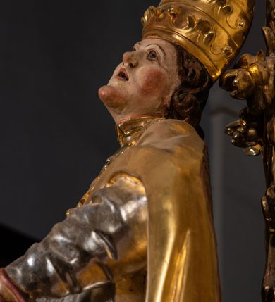 Zdjęcie nr 23: Ołtarz drewniany, prostopadłościenny z kamienną mensą, z kamiennym portatylem. Antependium z prostokątną płyciną ujętą marmoryzowaną ramą ze złoconym karbowanym profilem. W polu medalion w formie stojącego owalu z przedstawieniem zakonnika z dzieciątkiem, flankowany akantową wicią akantową przeplataną z roślinną, na jasnoniebieskim tle. Nastawa ołtarzowa architektoniczna, jednoosiowa, jednokondygnacyjna ze zwieńczeniem na dwustrefowym cokole.  Retabulum flankowane parą opilastrowanych filarów, które dźwigają imposty oraz fragmenty przerwanego półkolistego przyczółka z siedzącymi puttami. Na tle filarów, na konsolach ustawione 2 figury papieża i biskupa. Trzony pilastrów dekorowane zwisami kwiatowymi. W Polu środkowym wnęka w formie stojącego prostokąta zamkniętego łukiem segmentowym nadwieszonego z uskokiem ujęta profilowaną ramą, dekorowaną ornamentem roślinnym, z obrazem świętego Marka. Wnęka od dołu i góry flankowana ornamentem roślinnym i roccailem. Kondygnacja flankowana uszami utworzonymi z roccailu. Zwieńczenie w formie zbliżonej do trapezu o wklęsłych bokach zamknięte fragmentem gzymsu, wyłamanego na kształt łuku segmentowego nadwieszonego, z kartuszem z ornamentem roccailowym. W polu gorejące serce w otoku z obłoków i uskrzydlonych główek anielskich, w glorii promienistej.  Struktura polichromowana w sposób imitujący marmoryzację w kolorze beżowo-zielonym. Ornamentyka i profile złocone, detal i zwieńczenie srebrzone.