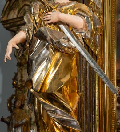 Zdjęcie nr 3: Ołtarz drewniany, prostopadłościenny z kamienną mensą, z kamiennym portatylem. Antepedium drewniane podzielone na trzy płyciny za pomocą pilastrów: w środkowej krzyż, kotwica i gorejące serce, w bocznych gorejące serce w koronie cierniowej i wieńcu z róż. Nastawa ołtarzowa architektoniczna, jednoosiowa, jednokondygnacyjna ze zwieńczeniem na cokole.  Retabulum flankowane parą zdwojonych pilastrów zakończonych konsolami,  które dźwigają pełne belkowanie oraz fragmenty przerwanego półkolistego przyczółka z siedzącymi puttami. Na tle pilastrów, na konsolach ustawione 2 figury: św. Katarzyny oraz Barbary. Trzony pilastrów dekorowane kampanulami. W Polu środkowym wnęka w formie stojącego prostokąta zamkniętego łukiem segmentowym nadwieszonego z uskokiem ujęta profilowaną ramą, z obrazem świętej Zofii z córkami, w osobnej ramie. Nad wnęką baldachim dekorowany lambrekinem, z podwieszoną tkaniną po dwóch stronach, lamowaną frędzlą. Nam baldachimem kartusz z uskrzydlonymi główkami anielskimi i zwieńczony koroną. Zwieńczenie w formie zbliżonej do trapezu o wklęsłych bokach zamknięte falistym gzymsem, dekorowanym uskrzydloną główką anielską, ujętą wolutami na tle muszli, z podwieszonymi kampanulami. W polu gołębica w otoku z obłoków i uskrzydlonych główek anielskich, w glorii promienistej.  Struktura polichromowana w sposób imitujący marmoryzację w kolorze beżowo-zielonym. Ornamentyka i profile złocone, detal i zwieńczenie srebrzone.