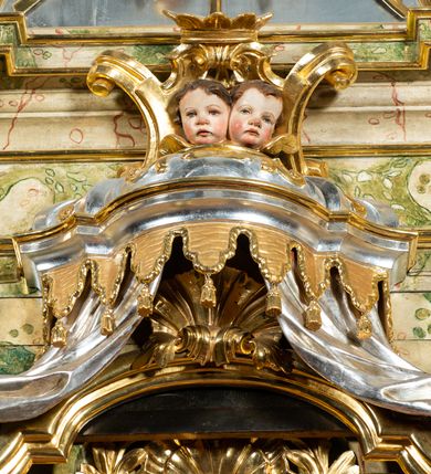 Zdjęcie nr 57: Ołtarz drewniany, prostopadłościenny z kamienną mensą, z kamiennym portatylem. Antepedium drewniane podzielone na trzy płyciny za pomocą pilastrów: w środkowej krzyż, kotwica i gorejące serce, w bocznych gorejące serce w koronie cierniowej i wieńcu z róż. Nastawa ołtarzowa architektoniczna, jednoosiowa, jednokondygnacyjna ze zwieńczeniem na cokole.  Retabulum flankowane parą zdwojonych pilastrów zakończonych konsolami,  które dźwigają pełne belkowanie oraz fragmenty przerwanego półkolistego przyczółka z siedzącymi puttami. Na tle pilastrów, na konsolach ustawione 2 figury: św. Katarzyny oraz Barbary. Trzony pilastrów dekorowane kampanulami. W Polu środkowym wnęka w formie stojącego prostokąta zamkniętego łukiem segmentowym nadwieszonego z uskokiem ujęta profilowaną ramą, z obrazem świętej Zofii z córkami, w osobnej ramie. Nad wnęką baldachim dekorowany lambrekinem, z podwieszoną tkaniną po dwóch stronach, lamowaną frędzlą. Nam baldachimem kartusz z uskrzydlonymi główkami anielskimi i zwieńczony koroną. Zwieńczenie w formie zbliżonej do trapezu o wklęsłych bokach zamknięte falistym gzymsem, dekorowanym uskrzydloną główką anielską, ujętą wolutami na tle muszli, z podwieszonymi kampanulami. W polu gołębica w otoku z obłoków i uskrzydlonych główek anielskich, w glorii promienistej.  Struktura polichromowana w sposób imitujący marmoryzację w kolorze beżowo-zielonym. Ornamentyka i profile złocone, detal i zwieńczenie srebrzone.