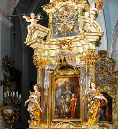 Zdjęcie nr 1: Ołtarz drewniany, prostopadłościenny z kamienną mensą, z kamiennym portatylem. Antepedium drewniane podzielone na trzy płyciny za pomocą pilastrów: w środkowej krzyż, kotwica i gorejące serce, w bocznych gorejące serce w koronie cierniowej i wieńcu z róż. Nastawa ołtarzowa architektoniczna, jednoosiowa, jednokondygnacyjna ze zwieńczeniem na cokole.  Retabulum flankowane parą zdwojonych pilastrów zakończonych konsolami,  które dźwigają pełne belkowanie oraz fragmenty przerwanego półkolistego przyczółka z siedzącymi puttami. Na tle pilastrów, na konsolach ustawione 2 figury: św. Katarzyny oraz Barbary. Trzony pilastrów dekorowane kampanulami. W Polu środkowym wnęka w formie stojącego prostokąta zamkniętego łukiem segmentowym nadwieszonego z uskokiem ujęta profilowaną ramą, z obrazem świętej Zofii z córkami, w osobnej ramie. Nad wnęką baldachim dekorowany lambrekinem, z podwieszoną tkaniną po dwóch stronach, lamowaną frędzlą. Nam baldachimem kartusz z uskrzydlonymi główkami anielskimi i zwieńczony koroną. Zwieńczenie w formie zbliżonej do trapezu o wklęsłych bokach zamknięte falistym gzymsem, dekorowanym uskrzydloną główką anielską, ujętą wolutami na tle muszli, z podwieszonymi kampanulami. W polu gołębica w otoku z obłoków i uskrzydlonych główek anielskich, w glorii promienistej.  Struktura polichromowana w sposób imitujący marmoryzację w kolorze beżowo-zielonym. Ornamentyka i profile złocone, detal i zwieńczenie srebrzone.