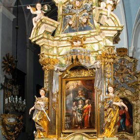 Zdjęcie nr 1: Ołtarz drewniany, prostopadłościenny z kamienną mensą, z kamiennym portatylem. Antepedium drewniane podzielone na trzy płyciny za pomocą pilastrów: w środkowej krzyż, kotwica i gorejące serce, w bocznych gorejące serce w koronie cierniowej i wieńcu z róż. Nastawa ołtarzowa architektoniczna, jednoosiowa, jednokondygnacyjna ze zwieńczeniem na cokole.  Retabulum flankowane parą zdwojonych pilastrów zakończonych konsolami,  które dźwigają pełne belkowanie oraz fragmenty przerwanego półkolistego przyczółka z siedzącymi puttami. Na tle pilastrów, na konsolach ustawione 2 figury: św. Katarzyny oraz Barbary. Trzony pilastrów dekorowane kampanulami. W Polu środkowym wnęka w formie stojącego prostokąta zamkniętego łukiem segmentowym nadwieszonego z uskokiem ujęta profilowaną ramą, z obrazem świętej Zofii z córkami, w osobnej ramie. Nad wnęką baldachim dekorowany lambrekinem, z podwieszoną tkaniną po dwóch stronach, lamowaną frędzlą. Nam baldachimem kartusz z uskrzydlonymi główkami anielskimi i zwieńczony koroną. Zwieńczenie w formie zbliżonej do trapezu o wklęsłych bokach zamknięte falistym gzymsem, dekorowanym uskrzydloną główką anielską, ujętą wolutami na tle muszli, z podwieszonymi kampanulami. W polu gołębica w otoku z obłoków i uskrzydlonych główek anielskich, w glorii promienistej.  Struktura polichromowana w sposób imitujący marmoryzację w kolorze beżowo-zielonym. Ornamentyka i profile złocone, detal i zwieńczenie srebrzone.