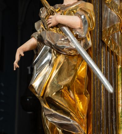 Zdjęcie nr 7: Ołtarz drewniany, prostopadłościenny z kamienną mensą, z kamiennym portatylem. Antepedium drewniane podzielone na trzy płyciny za pomocą pilastrów: w środkowej krzyż, kotwica i gorejące serce, w bocznych gorejące serce w koronie cierniowej i wieńcu z róż. Nastawa ołtarzowa architektoniczna, jednoosiowa, jednokondygnacyjna ze zwieńczeniem na cokole.  Retabulum flankowane parą zdwojonych pilastrów zakończonych konsolami,  które dźwigają pełne belkowanie oraz fragmenty przerwanego półkolistego przyczółka z siedzącymi puttami. Na tle pilastrów, na konsolach ustawione 2 figury: św. Katarzyny oraz Barbary. Trzony pilastrów dekorowane kampanulami. W Polu środkowym wnęka w formie stojącego prostokąta zamkniętego łukiem segmentowym nadwieszonego z uskokiem ujęta profilowaną ramą, z obrazem świętej Zofii z córkami, w osobnej ramie. Nad wnęką baldachim dekorowany lambrekinem, z podwieszoną tkaniną po dwóch stronach, lamowaną frędzlą. Nam baldachimem kartusz z uskrzydlonymi główkami anielskimi i zwieńczony koroną. Zwieńczenie w formie zbliżonej do trapezu o wklęsłych bokach zamknięte falistym gzymsem, dekorowanym uskrzydloną główką anielską, ujętą wolutami na tle muszli, z podwieszonymi kampanulami. W polu gołębica w otoku z obłoków i uskrzydlonych główek anielskich, w glorii promienistej.  Struktura polichromowana w sposób imitujący marmoryzację w kolorze beżowo-zielonym. Ornamentyka i profile złocone, detal i zwieńczenie srebrzone.