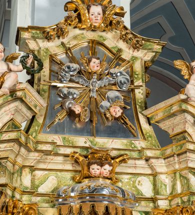 Zdjęcie nr 46: Ołtarz drewniany, prostopadłościenny z kamienną mensą, z kamiennym portatylem. Antepedium drewniane podzielone na trzy płyciny za pomocą pilastrów: w środkowej krzyż, kotwica i gorejące serce, w bocznych gorejące serce w koronie cierniowej i wieńcu z róż. Nastawa ołtarzowa architektoniczna, jednoosiowa, jednokondygnacyjna ze zwieńczeniem na cokole.  Retabulum flankowane parą zdwojonych pilastrów zakończonych konsolami,  które dźwigają pełne belkowanie oraz fragmenty przerwanego półkolistego przyczółka z siedzącymi puttami. Na tle pilastrów, na konsolach ustawione 2 figury: św. Katarzyny oraz Barbary. Trzony pilastrów dekorowane kampanulami. W Polu środkowym wnęka w formie stojącego prostokąta zamkniętego łukiem segmentowym nadwieszonego z uskokiem ujęta profilowaną ramą, z obrazem świętej Zofii z córkami, w osobnej ramie. Nad wnęką baldachim dekorowany lambrekinem, z podwieszoną tkaniną po dwóch stronach, lamowaną frędzlą. Nam baldachimem kartusz z uskrzydlonymi główkami anielskimi i zwieńczony koroną. Zwieńczenie w formie zbliżonej do trapezu o wklęsłych bokach zamknięte falistym gzymsem, dekorowanym uskrzydloną główką anielską, ujętą wolutami na tle muszli, z podwieszonymi kampanulami. W polu gołębica w otoku z obłoków i uskrzydlonych główek anielskich, w glorii promienistej.  Struktura polichromowana w sposób imitujący marmoryzację w kolorze beżowo-zielonym. Ornamentyka i profile złocone, detal i zwieńczenie srebrzone.