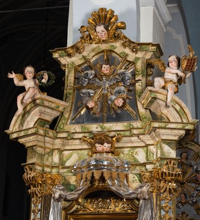 Zdjęcie nr 42: Ołtarz drewniany, prostopadłościenny z kamienną mensą, z kamiennym portatylem. Antepedium drewniane podzielone na trzy płyciny za pomocą pilastrów: w środkowej krzyż, kotwica i gorejące serce, w bocznych gorejące serce w koronie cierniowej i wieńcu z róż. Nastawa ołtarzowa architektoniczna, jednoosiowa, jednokondygnacyjna ze zwieńczeniem na cokole.  Retabulum flankowane parą zdwojonych pilastrów zakończonych konsolami,  które dźwigają pełne belkowanie oraz fragmenty przerwanego półkolistego przyczółka z siedzącymi puttami. Na tle pilastrów, na konsolach ustawione 2 figury: św. Katarzyny oraz Barbary. Trzony pilastrów dekorowane kampanulami. W Polu środkowym wnęka w formie stojącego prostokąta zamkniętego łukiem segmentowym nadwieszonego z uskokiem ujęta profilowaną ramą, z obrazem świętej Zofii z córkami, w osobnej ramie. Nad wnęką baldachim dekorowany lambrekinem, z podwieszoną tkaniną po dwóch stronach, lamowaną frędzlą. Nam baldachimem kartusz z uskrzydlonymi główkami anielskimi i zwieńczony koroną. Zwieńczenie w formie zbliżonej do trapezu o wklęsłych bokach zamknięte falistym gzymsem, dekorowanym uskrzydloną główką anielską, ujętą wolutami na tle muszli, z podwieszonymi kampanulami. W polu gołębica w otoku z obłoków i uskrzydlonych główek anielskich, w glorii promienistej.  Struktura polichromowana w sposób imitujący marmoryzację w kolorze beżowo-zielonym. Ornamentyka i profile złocone, detal i zwieńczenie srebrzone.