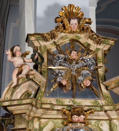 Zdjęcie nr 45: Ołtarz drewniany, prostopadłościenny z kamienną mensą, z kamiennym portatylem. Antepedium drewniane podzielone na trzy płyciny za pomocą pilastrów: w środkowej krzyż, kotwica i gorejące serce, w bocznych gorejące serce w koronie cierniowej i wieńcu z róż. Nastawa ołtarzowa architektoniczna, jednoosiowa, jednokondygnacyjna ze zwieńczeniem na cokole.  Retabulum flankowane parą zdwojonych pilastrów zakończonych konsolami,  które dźwigają pełne belkowanie oraz fragmenty przerwanego półkolistego przyczółka z siedzącymi puttami. Na tle pilastrów, na konsolach ustawione 2 figury: św. Katarzyny oraz Barbary. Trzony pilastrów dekorowane kampanulami. W Polu środkowym wnęka w formie stojącego prostokąta zamkniętego łukiem segmentowym nadwieszonego z uskokiem ujęta profilowaną ramą, z obrazem świętej Zofii z córkami, w osobnej ramie. Nad wnęką baldachim dekorowany lambrekinem, z podwieszoną tkaniną po dwóch stronach, lamowaną frędzlą. Nam baldachimem kartusz z uskrzydlonymi główkami anielskimi i zwieńczony koroną. Zwieńczenie w formie zbliżonej do trapezu o wklęsłych bokach zamknięte falistym gzymsem, dekorowanym uskrzydloną główką anielską, ujętą wolutami na tle muszli, z podwieszonymi kampanulami. W polu gołębica w otoku z obłoków i uskrzydlonych główek anielskich, w glorii promienistej.  Struktura polichromowana w sposób imitujący marmoryzację w kolorze beżowo-zielonym. Ornamentyka i profile złocone, detal i zwieńczenie srebrzone.