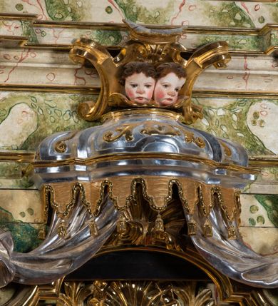 Zdjęcie nr 49: Ołtarz drewniany, prostopadłościenny z kamienną mensą, z kamiennym portatylem. Antepedium drewniane podzielone na trzy płyciny za pomocą pilastrów: w środkowej krzyż, kotwica i gorejące serce, w bocznych gorejące serce w koronie cierniowej i wieńcu z róż. Nastawa ołtarzowa architektoniczna, jednoosiowa, jednokondygnacyjna ze zwieńczeniem na cokole.  Retabulum flankowane parą zdwojonych pilastrów zakończonych konsolami,  które dźwigają pełne belkowanie oraz fragmenty przerwanego półkolistego przyczółka z siedzącymi puttami. Na tle pilastrów, na konsolach ustawione 2 figury: św. Katarzyny oraz Barbary. Trzony pilastrów dekorowane kampanulami. W Polu środkowym wnęka w formie stojącego prostokąta zamkniętego łukiem segmentowym nadwieszonego z uskokiem ujęta profilowaną ramą, z obrazem świętej Zofii z córkami, w osobnej ramie. Nad wnęką baldachim dekorowany lambrekinem, z podwieszoną tkaniną po dwóch stronach, lamowaną frędzlą. Nam baldachimem kartusz z uskrzydlonymi główkami anielskimi i zwieńczony koroną. Zwieńczenie w formie zbliżonej do trapezu o wklęsłych bokach zamknięte falistym gzymsem, dekorowanym uskrzydloną główką anielską, ujętą wolutami na tle muszli, z podwieszonymi kampanulami. W polu gołębica w otoku z obłoków i uskrzydlonych główek anielskich, w glorii promienistej.  Struktura polichromowana w sposób imitujący marmoryzację w kolorze beżowo-zielonym. Ornamentyka i profile złocone, detal i zwieńczenie srebrzone.