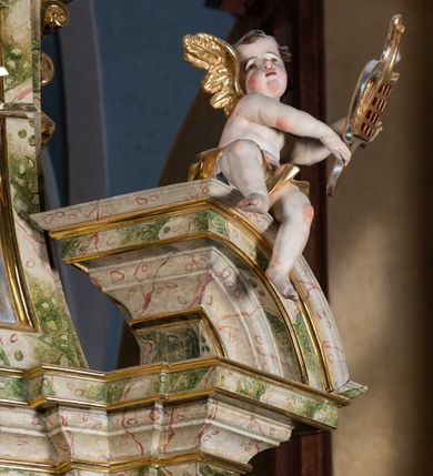 Zdjęcie nr 51: Ołtarz drewniany, prostopadłościenny z kamienną mensą, z kamiennym portatylem. Antepedium drewniane podzielone na trzy płyciny za pomocą pilastrów: w środkowej krzyż, kotwica i gorejące serce, w bocznych gorejące serce w koronie cierniowej i wieńcu z róż. Nastawa ołtarzowa architektoniczna, jednoosiowa, jednokondygnacyjna ze zwieńczeniem na cokole.  Retabulum flankowane parą zdwojonych pilastrów zakończonych konsolami,  które dźwigają pełne belkowanie oraz fragmenty przerwanego półkolistego przyczółka z siedzącymi puttami. Na tle pilastrów, na konsolach ustawione 2 figury: św. Katarzyny oraz Barbary. Trzony pilastrów dekorowane kampanulami. W Polu środkowym wnęka w formie stojącego prostokąta zamkniętego łukiem segmentowym nadwieszonego z uskokiem ujęta profilowaną ramą, z obrazem świętej Zofii z córkami, w osobnej ramie. Nad wnęką baldachim dekorowany lambrekinem, z podwieszoną tkaniną po dwóch stronach, lamowaną frędzlą. Nam baldachimem kartusz z uskrzydlonymi główkami anielskimi i zwieńczony koroną. Zwieńczenie w formie zbliżonej do trapezu o wklęsłych bokach zamknięte falistym gzymsem, dekorowanym uskrzydloną główką anielską, ujętą wolutami na tle muszli, z podwieszonymi kampanulami. W polu gołębica w otoku z obłoków i uskrzydlonych główek anielskich, w glorii promienistej.  Struktura polichromowana w sposób imitujący marmoryzację w kolorze beżowo-zielonym. Ornamentyka i profile złocone, detal i zwieńczenie srebrzone.