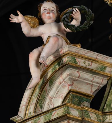 Zdjęcie nr 52: Ołtarz drewniany, prostopadłościenny z kamienną mensą, z kamiennym portatylem. Antepedium drewniane podzielone na trzy płyciny za pomocą pilastrów: w środkowej krzyż, kotwica i gorejące serce, w bocznych gorejące serce w koronie cierniowej i wieńcu z róż. Nastawa ołtarzowa architektoniczna, jednoosiowa, jednokondygnacyjna ze zwieńczeniem na cokole.  Retabulum flankowane parą zdwojonych pilastrów zakończonych konsolami,  które dźwigają pełne belkowanie oraz fragmenty przerwanego półkolistego przyczółka z siedzącymi puttami. Na tle pilastrów, na konsolach ustawione 2 figury: św. Katarzyny oraz Barbary. Trzony pilastrów dekorowane kampanulami. W Polu środkowym wnęka w formie stojącego prostokąta zamkniętego łukiem segmentowym nadwieszonego z uskokiem ujęta profilowaną ramą, z obrazem świętej Zofii z córkami, w osobnej ramie. Nad wnęką baldachim dekorowany lambrekinem, z podwieszoną tkaniną po dwóch stronach, lamowaną frędzlą. Nam baldachimem kartusz z uskrzydlonymi główkami anielskimi i zwieńczony koroną. Zwieńczenie w formie zbliżonej do trapezu o wklęsłych bokach zamknięte falistym gzymsem, dekorowanym uskrzydloną główką anielską, ujętą wolutami na tle muszli, z podwieszonymi kampanulami. W polu gołębica w otoku z obłoków i uskrzydlonych główek anielskich, w glorii promienistej.  Struktura polichromowana w sposób imitujący marmoryzację w kolorze beżowo-zielonym. Ornamentyka i profile złocone, detal i zwieńczenie srebrzone.