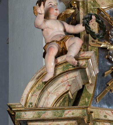 Zdjęcie nr 53: Ołtarz drewniany, prostopadłościenny z kamienną mensą, z kamiennym portatylem. Antepedium drewniane podzielone na trzy płyciny za pomocą pilastrów: w środkowej krzyż, kotwica i gorejące serce, w bocznych gorejące serce w koronie cierniowej i wieńcu z róż. Nastawa ołtarzowa architektoniczna, jednoosiowa, jednokondygnacyjna ze zwieńczeniem na cokole.  Retabulum flankowane parą zdwojonych pilastrów zakończonych konsolami,  które dźwigają pełne belkowanie oraz fragmenty przerwanego półkolistego przyczółka z siedzącymi puttami. Na tle pilastrów, na konsolach ustawione 2 figury: św. Katarzyny oraz Barbary. Trzony pilastrów dekorowane kampanulami. W Polu środkowym wnęka w formie stojącego prostokąta zamkniętego łukiem segmentowym nadwieszonego z uskokiem ujęta profilowaną ramą, z obrazem świętej Zofii z córkami, w osobnej ramie. Nad wnęką baldachim dekorowany lambrekinem, z podwieszoną tkaniną po dwóch stronach, lamowaną frędzlą. Nam baldachimem kartusz z uskrzydlonymi główkami anielskimi i zwieńczony koroną. Zwieńczenie w formie zbliżonej do trapezu o wklęsłych bokach zamknięte falistym gzymsem, dekorowanym uskrzydloną główką anielską, ujętą wolutami na tle muszli, z podwieszonymi kampanulami. W polu gołębica w otoku z obłoków i uskrzydlonych główek anielskich, w glorii promienistej.  Struktura polichromowana w sposób imitujący marmoryzację w kolorze beżowo-zielonym. Ornamentyka i profile złocone, detal i zwieńczenie srebrzone.