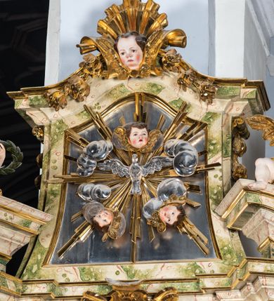 Zdjęcie nr 59: Ołtarz drewniany, prostopadłościenny z kamienną mensą, z kamiennym portatylem. Antepedium drewniane podzielone na trzy płyciny za pomocą pilastrów: w środkowej krzyż, kotwica i gorejące serce, w bocznych gorejące serce w koronie cierniowej i wieńcu z róż. Nastawa ołtarzowa architektoniczna, jednoosiowa, jednokondygnacyjna ze zwieńczeniem na cokole.  Retabulum flankowane parą zdwojonych pilastrów zakończonych konsolami,  które dźwigają pełne belkowanie oraz fragmenty przerwanego półkolistego przyczółka z siedzącymi puttami. Na tle pilastrów, na konsolach ustawione 2 figury: św. Katarzyny oraz Barbary. Trzony pilastrów dekorowane kampanulami. W Polu środkowym wnęka w formie stojącego prostokąta zamkniętego łukiem segmentowym nadwieszonego z uskokiem ujęta profilowaną ramą, z obrazem świętej Zofii z córkami, w osobnej ramie. Nad wnęką baldachim dekorowany lambrekinem, z podwieszoną tkaniną po dwóch stronach, lamowaną frędzlą. Nam baldachimem kartusz z uskrzydlonymi główkami anielskimi i zwieńczony koroną. Zwieńczenie w formie zbliżonej do trapezu o wklęsłych bokach zamknięte falistym gzymsem, dekorowanym uskrzydloną główką anielską, ujętą wolutami na tle muszli, z podwieszonymi kampanulami. W polu gołębica w otoku z obłoków i uskrzydlonych główek anielskich, w glorii promienistej.  Struktura polichromowana w sposób imitujący marmoryzację w kolorze beżowo-zielonym. Ornamentyka i profile złocone, detal i zwieńczenie srebrzone.