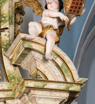 Zdjęcie nr 60: Ołtarz drewniany, prostopadłościenny z kamienną mensą, z kamiennym portatylem. Antepedium drewniane podzielone na trzy płyciny za pomocą pilastrów: w środkowej krzyż, kotwica i gorejące serce, w bocznych gorejące serce w koronie cierniowej i wieńcu z róż. Nastawa ołtarzowa architektoniczna, jednoosiowa, jednokondygnacyjna ze zwieńczeniem na cokole.  Retabulum flankowane parą zdwojonych pilastrów zakończonych konsolami,  które dźwigają pełne belkowanie oraz fragmenty przerwanego półkolistego przyczółka z siedzącymi puttami. Na tle pilastrów, na konsolach ustawione 2 figury: św. Katarzyny oraz Barbary. Trzony pilastrów dekorowane kampanulami. W Polu środkowym wnęka w formie stojącego prostokąta zamkniętego łukiem segmentowym nadwieszonego z uskokiem ujęta profilowaną ramą, z obrazem świętej Zofii z córkami, w osobnej ramie. Nad wnęką baldachim dekorowany lambrekinem, z podwieszoną tkaniną po dwóch stronach, lamowaną frędzlą. Nam baldachimem kartusz z uskrzydlonymi główkami anielskimi i zwieńczony koroną. Zwieńczenie w formie zbliżonej do trapezu o wklęsłych bokach zamknięte falistym gzymsem, dekorowanym uskrzydloną główką anielską, ujętą wolutami na tle muszli, z podwieszonymi kampanulami. W polu gołębica w otoku z obłoków i uskrzydlonych główek anielskich, w glorii promienistej.  Struktura polichromowana w sposób imitujący marmoryzację w kolorze beżowo-zielonym. Ornamentyka i profile złocone, detal i zwieńczenie srebrzone.