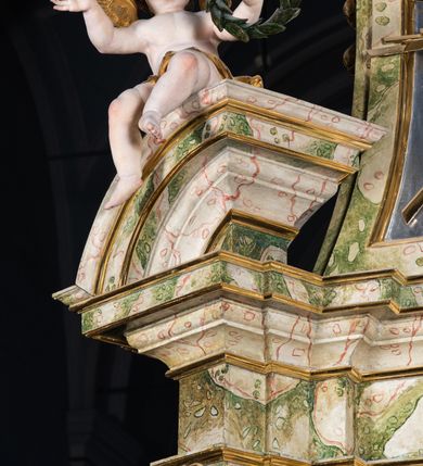 Zdjęcie nr 58: Ołtarz drewniany, prostopadłościenny z kamienną mensą, z kamiennym portatylem. Antepedium drewniane podzielone na trzy płyciny za pomocą pilastrów: w środkowej krzyż, kotwica i gorejące serce, w bocznych gorejące serce w koronie cierniowej i wieńcu z róż. Nastawa ołtarzowa architektoniczna, jednoosiowa, jednokondygnacyjna ze zwieńczeniem na cokole.  Retabulum flankowane parą zdwojonych pilastrów zakończonych konsolami,  które dźwigają pełne belkowanie oraz fragmenty przerwanego półkolistego przyczółka z siedzącymi puttami. Na tle pilastrów, na konsolach ustawione 2 figury: św. Katarzyny oraz Barbary. Trzony pilastrów dekorowane kampanulami. W Polu środkowym wnęka w formie stojącego prostokąta zamkniętego łukiem segmentowym nadwieszonego z uskokiem ujęta profilowaną ramą, z obrazem świętej Zofii z córkami, w osobnej ramie. Nad wnęką baldachim dekorowany lambrekinem, z podwieszoną tkaniną po dwóch stronach, lamowaną frędzlą. Nam baldachimem kartusz z uskrzydlonymi główkami anielskimi i zwieńczony koroną. Zwieńczenie w formie zbliżonej do trapezu o wklęsłych bokach zamknięte falistym gzymsem, dekorowanym uskrzydloną główką anielską, ujętą wolutami na tle muszli, z podwieszonymi kampanulami. W polu gołębica w otoku z obłoków i uskrzydlonych główek anielskich, w glorii promienistej.  Struktura polichromowana w sposób imitujący marmoryzację w kolorze beżowo-zielonym. Ornamentyka i profile złocone, detal i zwieńczenie srebrzone.