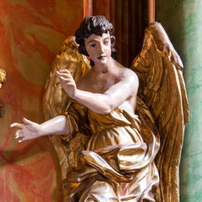 Zdjęcie nr 1: Para pełnoplastycznych figur ustawionych na niewielkich, prostopadłościennych postumentach. Postaci przedstawione w pozycji stojącej, w kontrapoście. Aniołowie ukazani jako ciemnowłosi młodzieńcy o owalnych twarzach ubrani w złote szaty tworzące dynamicznie wyginające się fałdy. Torsy odsłonięte, stopy bose. Anioł z lewej strony ołtarza unosi prawą rękę do góry w geście oratorskim, lewą ugiętą w łokciu wyciąga przed siebie. Lewa noga ugięta w kolanie. Anioł z prawej strony obie ręce ugięte w łokciach wyciąga w prawo. Szaty i skrzydła złocone, karnacje aniołów polichromowane.