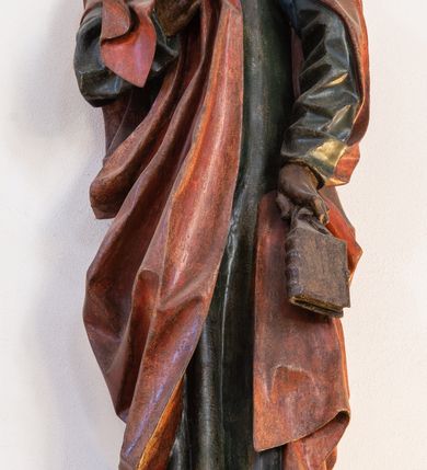 Zdjęcie nr 17: Rzeźba przedstawiająca ukrzyżowanego Chrystusa o ciele ukazanym w delikatnym zwisie ze szczupłymi, wyprężonymi ramionami tworzącymi zarys litery „V”. Głowa Zbawiciela pochylona na prawe ramię z umieszczoną na niej cierniową koroną w formie kołpaka i złoconym nimbem promienistym. Twarz Chrystusa szczupła, oczy zamknięte, nos długi prosty, usta otwarte. Długie, ciemne włosy spływają na prawe ramię długim, skręconym lokiem. Zarost krótki, ciemnobrązowy. Ciało Chrystusa z widoczną raną w prawym boku oddane realistycznie, stopy przebite jednym gwoździem. Wokół bioder udrapowane krótkie, złocone perizonium tworzące płytkie fałdy. U szczytu pionowej belki krzyża titulus w formie banderoli z napisem „INRI”. Krzyż prosty, drewniany w kolorze ciemnobrązowym. Figura w pełni polichromowana, perizonium i nimb złocone.