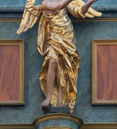 Zdjęcie nr 3: Chór muzyczny konstrukcji drewnianej, wparty na dwóch kamiennych kolumnach o prostych impostowych kapitelach. Balustrada chóru pełna o dekoracji płycinowej (naprzemiennie płyciny owalne, prostokątna i sześcioboczne), zwieńczona profilowanym gzymsem. W dołu ażurowa, wycinana dekoracja. Część środkowa parapetu przełamana i wysunięta do przodu z ustawionymi na niewielkich konsolach polichromowanymi, złoconymi i srebrzonymi figurami: anioła (po środku), św. Wojciecha (?) z lewej i św. Stanisława z prawej. Struktura marmoryzowana w odcieniach zgaszonego niebieskiego, wnętrza płycin w kolorze ceglastej czerwieni. Organy o formie architektonicznej, dziewięcioosiowe z zaakcentowanymi osiami nieparzystymi. Dekorowane złoconym ornamentem akantowym, palmetami, girlandami oraz rocaille&#039;m. Osie trzecia i siódma dodatkowe zwieńczone złoconymi wazonami. Struktura marmoryzowana w odcieniach zgaszonego koloru niebieskiego.