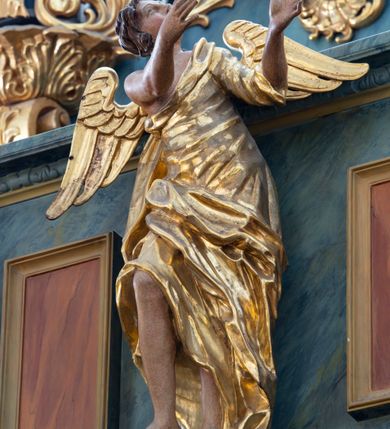 Zdjęcie nr 7: Chór muzyczny konstrukcji drewnianej, wparty na dwóch kamiennych kolumnach o prostych impostowych kapitelach. Balustrada chóru pełna o dekoracji płycinowej (naprzemiennie płyciny owalne, prostokątna i sześcioboczne), zwieńczona profilowanym gzymsem. W dołu ażurowa, wycinana dekoracja. Część środkowa parapetu przełamana i wysunięta do przodu z ustawionymi na niewielkich konsolach polichromowanymi, złoconymi i srebrzonymi figurami: anioła (po środku), św. Wojciecha (?) z lewej i św. Stanisława z prawej. Struktura marmoryzowana w odcieniach zgaszonego niebieskiego, wnętrza płycin w kolorze ceglastej czerwieni. Organy o formie architektonicznej, dziewięcioosiowe z zaakcentowanymi osiami nieparzystymi. Dekorowane złoconym ornamentem akantowym, palmetami, girlandami oraz rocaille'm. Osie trzecia i siódma dodatkowe zwieńczone złoconymi wazonami. Struktura marmoryzowana w odcieniach zgaszonego koloru niebieskiego.