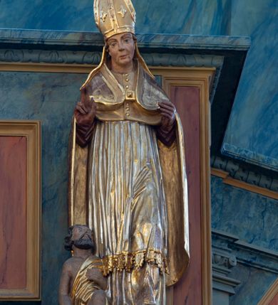 Zdjęcie nr 8: Chór muzyczny konstrukcji drewnianej, wparty na dwóch kamiennych kolumnach o prostych impostowych kapitelach. Balustrada chóru pełna o dekoracji płycinowej (naprzemiennie płyciny owalne, prostokątna i sześcioboczne), zwieńczona profilowanym gzymsem. W dołu ażurowa, wycinana dekoracja. Część środkowa parapetu przełamana i wysunięta do przodu z ustawionymi na niewielkich konsolach polichromowanymi, złoconymi i srebrzonymi figurami: anioła (po środku), św. Wojciecha (?) z lewej i św. Stanisława z prawej. Struktura marmoryzowana w odcieniach zgaszonego niebieskiego, wnętrza płycin w kolorze ceglastej czerwieni. Organy o formie architektonicznej, dziewięcioosiowe z zaakcentowanymi osiami nieparzystymi. Dekorowane złoconym ornamentem akantowym, palmetami, girlandami oraz rocaille&#039;m. Osie trzecia i siódma dodatkowe zwieńczone złoconymi wazonami. Struktura marmoryzowana w odcieniach zgaszonego koloru niebieskiego.