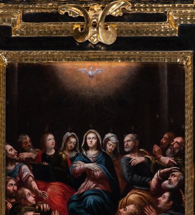 Zdjęcie nr 1: Obraz w kształcie stojącego prostokąta ujętego czarno-złotą ramą z uszakami i dekoracją w postaci złoconych wolut w zwieńczeniu oraz po bokach. Scena Zesłania Ducha Świętego rozgrywa się w ciemnym pomieszczeniu ujętym po bokach kolumnami. Na zgromadzonych w wieczerniku Marię ukazaną w centrum kompozycji, siedzące po jej bokach dwie kobiety oraz otaczających ich w półokręgu 12 apostołów spływają płomyki ognia. W górnej części kompozycji, na tle świetlistej glorii, ukazana gołębica Ducha Świętego. Maria przedstawiona jako młoda kobieta z uniesioną do góry głową i rękami skrzyżowanymi na wysokości piersi. Ubrana jest w jasnoróżową suknię z długimi rękawami oraz niebieski płaszcz. Na jasne włosy ma narzuconą białą chustę. Stopy Matki Boskiej są bose. Nieco z tyłu za Marią przedstawiono dwie młode kobiety z pochylonymi do dołu głowami okrytymi białymi chustami. Po prawej stronie Marki Boskiej przedstawiony św. Jan Ewangelista wyobrażony jako młody, jasnowłosy mężczyzna o owalnej twarzy i delikatnych rysach. Św. Jan odwraca głowę w lewo i unosi wzrok ku górze. W ręku trzyma otwartą księgę. Święty ubrany jest w zielone szaty z długimi rękawami oraz intensywnie czerwony płaszcz. Po lewej stronie Marii ukazano św. Piotra, który odwraca głowę w prawo i unosi wzrok ku górze. Prawą dłoń składa na piersi. Świętego przedstawiono jako starszego mężczyznę z krótką, siwą brodą i łysiną ponad czołem, Ubrany jest w ciemnoszare szaty z długimi rękawami i żółty płaszcz. Pozostali apostołowie tworzą dwie pięcioosobowe grupy rozmieszczone po prawej i lewej stronie kompozycji. Postaci o zróżnicowanych typach fizjonomicznych ukazane zostały z dynamicznych pozach z głowami uniesionymi w kierunku gołębicy Ducha Świętego. Tło jednolicie ciemne. Kolorystyka obrazu ciemnam nasycona.